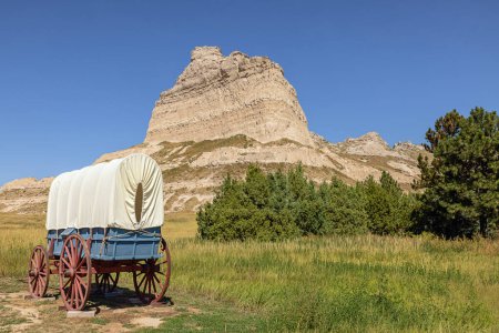 Photo for Wagon on display along the Oregon Trail at the entrance of the Mitchell Pass in the vicinity of Sotts Bluff National Monument with Eagle Rock on the right - Royalty Free Image