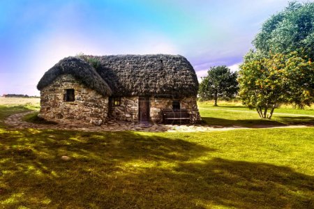 Foto de Contempla el encanto rústico de Leanach Cottage, una estructura de techo de paja situada en el histórico campo de batalla de Culloden en Escocia. Construido en 1760, la casa se presenta en casi todos los contemporáneos - Imagen libre de derechos