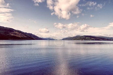 Photo for Experience the sublime beauty of Scotland with this high-depth-of-field photograph showcasing the textured waters of Loch Ness, a boat gracefully sailing, and rolling hills forming the backdrop. This - Royalty Free Image