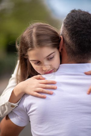 Daughter tenderly hugs her father, resting her head on his shoulder