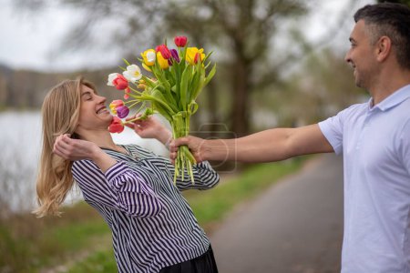 Mann schenkt Frau hellen Strauß von Tulpen, drückt Gefühle und Fürsorge aus