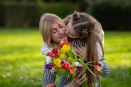 Mère et fille avec des tulipes, fille embrasser mère.