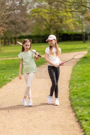 Photo for Two girls with badminton rackets on a park path - Royalty Free Image