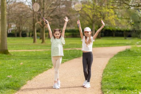Téléchargez les photos : Deux filles posant avec des raquettes de badminton dans le parc. - en image libre de droit