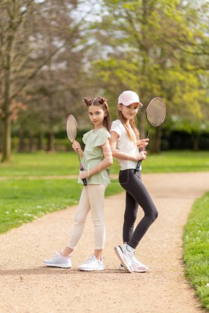 Photo for Two girls posing with badminton rackets in the park. - Royalty Free Image