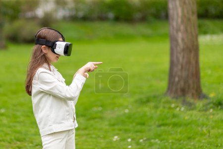 Girl in virtual reality headset pointing in a park.