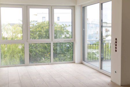 Leerer Raum im Neubau mit unvollendeter Renovierung und großen Fenstern