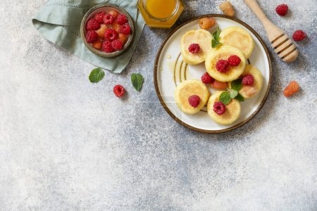 Photo for Homemade cottage cheese pancakes gluten free (syrniki, curd fritters) with berries on a stone background. Ricotta pancakes, morning breakfast table. View from above. Copy space. - Royalty Free Image