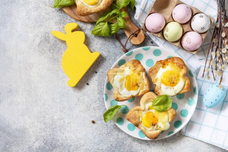 Idea de desayuno de Pascua. Huevos revueltos en hojaldre con queso y tocino sobre un fondo de piedra. Vista desde arriba. Copiar espacio.