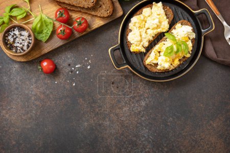 Photo for Scrambled eggs on whole grain bread. Homemade breakfast or brunch meal - scrambled eggs. View from above. Copy space. - Royalty Free Image