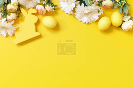 Foto de Composición de Pascua con huevos coloridos, conejito de madera y flores de primavera sobre fondo amarillo. Vista desde arriba. Copiar espacio. - Imagen libre de derechos