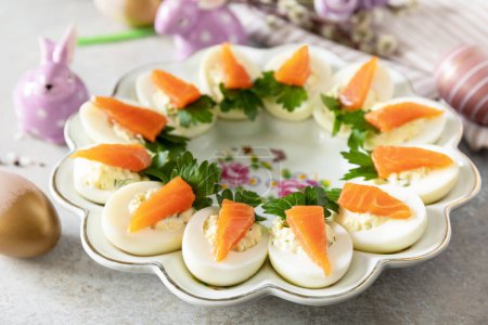 Stuffed eggs with cheese and salted salmon in the form of a carrot. Festive dinner, Easter brunch.