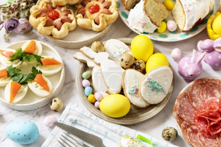 Foto de Cena festiva, almuerzo de Pascua. Escena de mesa de Pascua con una variedad de hornear, postres, huevos rellenos y huevos teñidos sobre un fondo de mármol. - Imagen libre de derechos