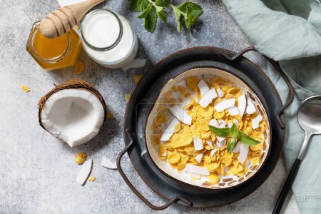 Photo for Summer vegan breakfast. Cereal granola breakfast flakes with coconut non-dairy alternative milk and fresh coconut slices on a stone tabletop. View from above. - Royalty Free Image