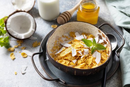Photo for Summer vegan breakfast. Cereal granola breakfast flakes with coconut non-dairy alternative milk and fresh coconut slices on a stone tabletop. Copy space. - Royalty Free Image