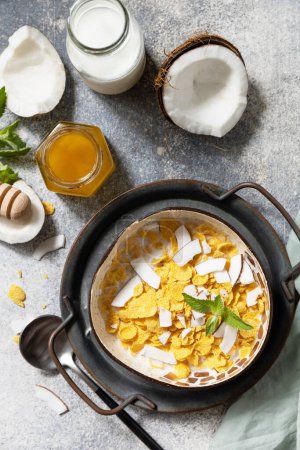 Photo for Vegan healthy breakfast. Cereal granola breakfast flakes with coconut non-dairy alternative milk and fresh coconut slices on a stone tabletop. View from above. - Royalty Free Image