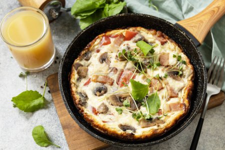 Photo for Rustic omelette (frittata) with mushrooms and bacon on a cast iron pan. Italian breakfast dish. - Royalty Free Image