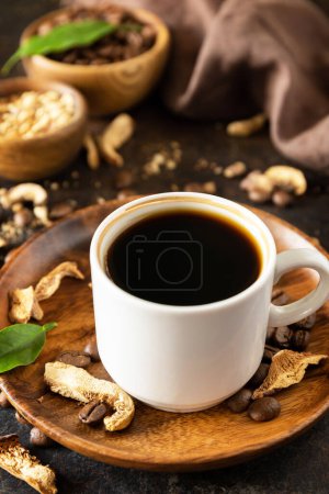 Healthy organic energizing adaptogen. Mushroom coffee in a cup and coffee beans, trendy drink on a stone background. 