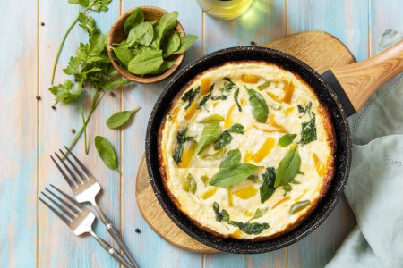 Photo for Healthy frittata or stuffed omelette in pan on rustic wooden background. Italian omelette with organic spinach and bell pepper. View from above. - Royalty Free Image