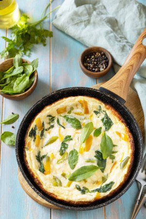 Photo for Healthy frittata or stuffed omelette in pan on rustic wooden background. Italian omelette with organic spinach and bell pepper. - Royalty Free Image