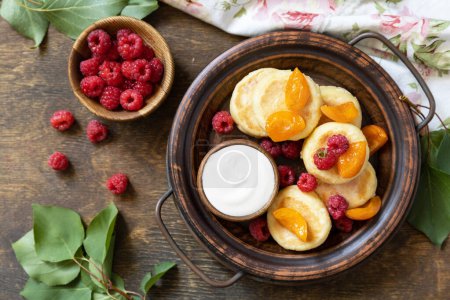Photo for Healthy and delicious morning breakfast. Homemade cottage cheese pancakes gluten free (syrniki, curd fritters) with berries on wooden rustic background. View from above. - Royalty Free Image