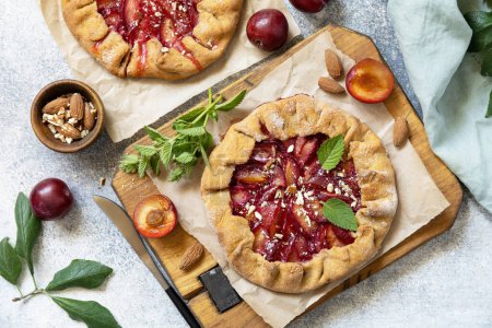 Photo for Plum Galette. Healthy homemade wholegrain fruit pie (galette) with plums and almonds, vegan vegetarian dessert on a stone table. View from above. - Royalty Free Image