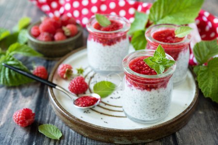 Photo for Healthy breakfast. Glass jars with chia pudding with raspberry and jam or smoothies with chia seeds on rustic table. - Royalty Free Image