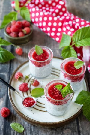 Photo for Healthy breakfast. Glass jars with chia pudding with raspberry and jam or smoothies with chia seeds on rustic table. - Royalty Free Image