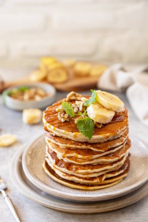 Photo for Celebrating Pancake day, american homemade breakfast. Banana gluten free pancakes with nuts and caramel on stone tabletop. Copy space. - Royalty Free Image