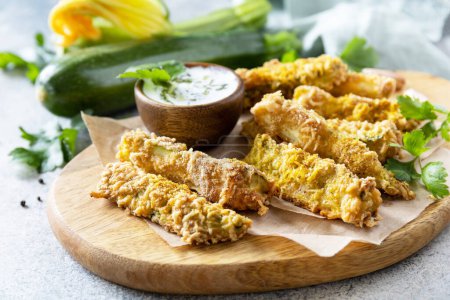 Photo for Healthy tasty snack, summer food. Zucchini fries. Crispy Zucchini sticks in breadcrumbs, with cheese with garlic yogurt sause. - Royalty Free Image
