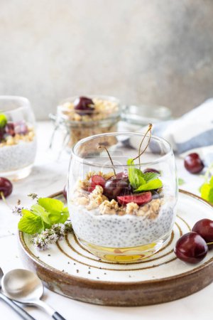 Photo for Healthy menu concept. Home made granola breakfast. Glass of parfait made of granola, berries cherry, yogurt with chia seeds on rustic table. Copy space. - Royalty Free Image