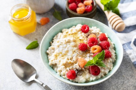 Photo for Oatmeal porridge in ceramic bowl decorated with fresh berries raspberries and chia seeds served with honey. Healthy diet breakfast. - Royalty Free Image