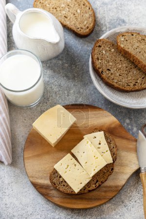 Téléchargez les photos : Concept d'aliments sains, petit déjeuner, superaliments. Pain à grains entiers frais au fromage et un verre de lait d'amande sur une table en pierre. - en image libre de droit