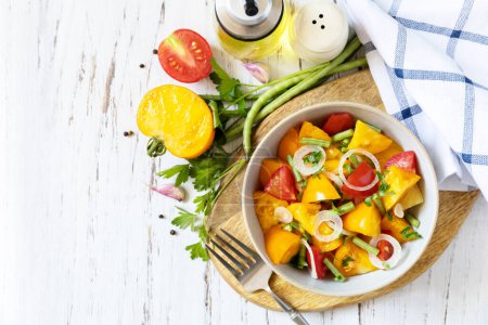 Photo for The concept of vegan or diet food. Tomato salad made from a mix of red and yellow tomatoes and green beans on a wooden table. View from above. Copy space. - Royalty Free Image