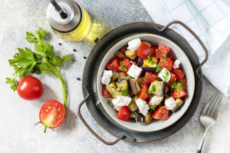 Téléchargez les photos : Alimentation saine végétarienne. Salade avec aubergines grillées, tomates et fromage feta sur une table en pierre grise. Vue d'en haut. - en image libre de droit