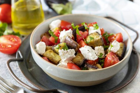 Téléchargez les photos : Alimentation saine végétarienne. Salade avec aubergines grillées, tomates et fromage feta sur une table en pierre grise. - en image libre de droit