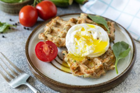 Photo for Spinach and zucchini vegan waffles with a poached egg on a stone tabletop. The concept of dietary and healthy breakfast. - Royalty Free Image