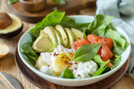 Photo for Delicious breakfast or lunch bowl with salted salmon fish, avocado, boiled egg and spinach on a rustic table. Ketogenic, keto or paleo diet. - Royalty Free Image