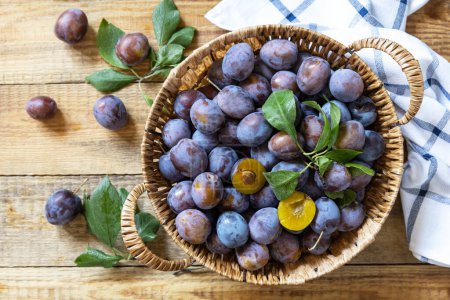 Photo for Fruit background, organic fruits. Still life food. Basket of fresh blue plums on a rustic wooden table. View from above. - Royalty Free Image