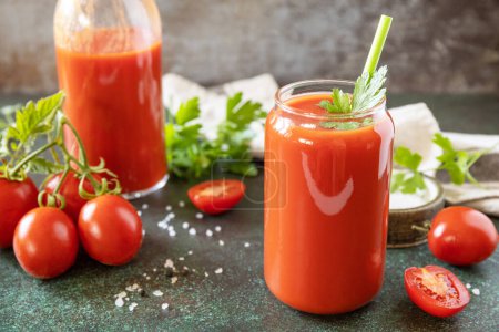 Foto de Otoño vitamina bebida jugo de tomate. El jugo de tomate en un vaso y los tomates frescos en una mesa de piedra. - Imagen libre de derechos