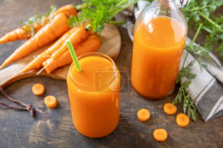 Photo for Fresh natural juice, healthy food concept. Glass jar of fresh carrot juice with fresh carrots on a rustic table. - Royalty Free Image