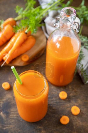 Photo for Fresh natural juice, healthy food concept. Glass jar of fresh carrot juice with fresh carrots on a rustic table. - Royalty Free Image