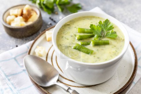 Foto de Puré de sopa vegana de verduras verdes. Comida saludable. Cuenco de frijol verde y sopa de crema de calabacín en una mesa de piedra. - Imagen libre de derechos
