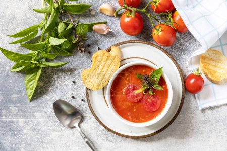 Photo for Vegetarian healthy diet. Vegan soup puree tomatoes. Bowl of tomato cream soup with basil and croutons on a stone table. View from above. - Royalty Free Image