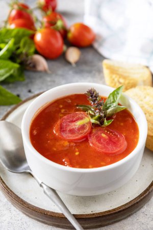 Foto de Sopa vegana puré de tomates. Dieta vegetariana saludable. Cuenco de sopa de crema de tomate con albahaca y croutons en una mesa de piedra. - Imagen libre de derechos