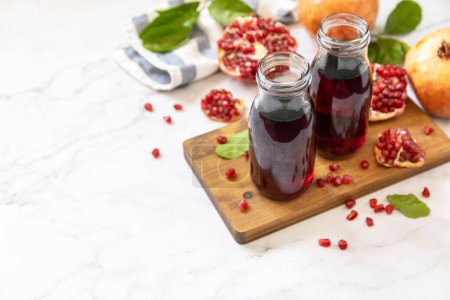 Photo for Healthy drink diet immunity vitamins or vegetarian food concept. Pomegranate juice in glass bottles and fresh pomegranate fruits. Copy space. - Royalty Free Image