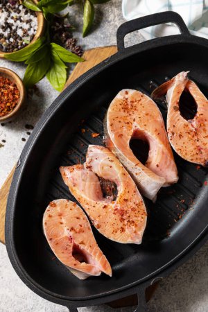 Foto de Pieces of fresh salmon fillet with spices on a grill pan. Seafood, culinary background. - Imagen libre de derechos