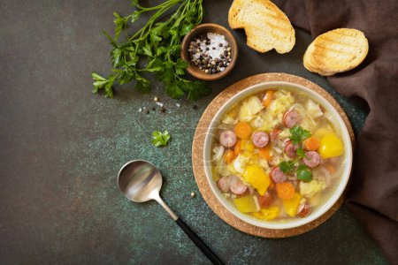 Téléchargez les photos : Soupe traditionnelle au chou Zelnacka avec des saucisses et des légumes dans un bol sur une table en pierre. Cuisine tchèque. Vue d'en haut. Espace de copie. - en image libre de droit