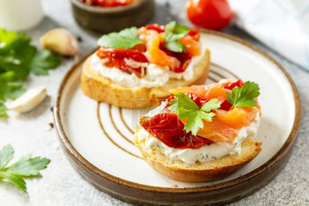 Photo for Open sandwiches or bruschetta with salted salmon, cheese and sun dried tomato on a stone table. Healthy food, seafood. - Royalty Free Image