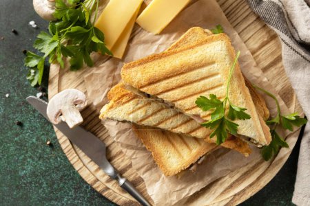 Foto de Delicioso sándwich con queso a la parrilla, tocino y champiñones. Desayuno casero en una mesa de piedra oscura. Vista desde arriba. - Imagen libre de derechos
